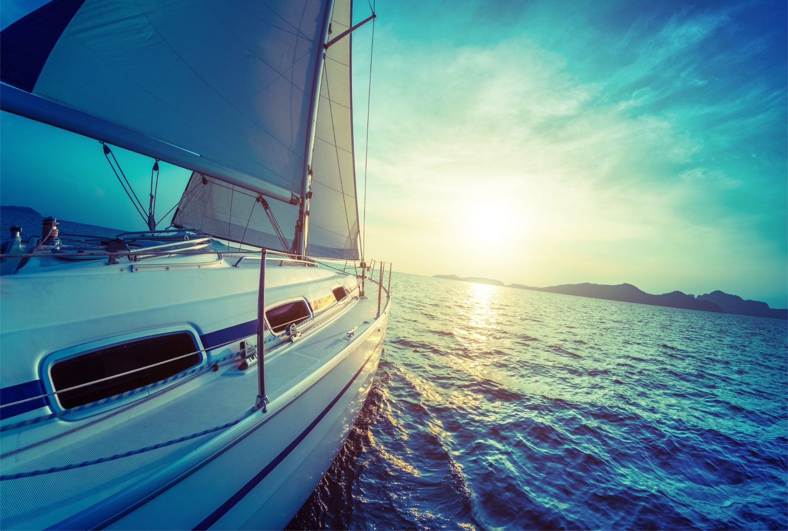 Barca a vela in navigazione verso l'orizzonte al tramonto