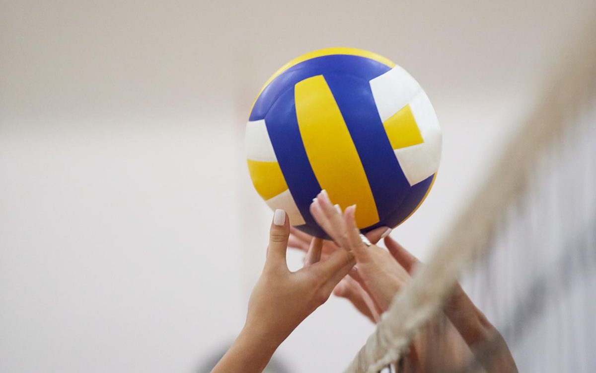 Mani che si contendono un pallone da pallavolo sopra la rete